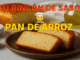 Pan de arroz casero recién horneado, cortado en rebanadas sobre plato marrón, acompañado de arroz, especias y aceite de oliva en fondo rústico.