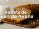 Pan de avena casero recién horneado sobre tabla de madera, con rebanada cortada y copos de avena en la corteza