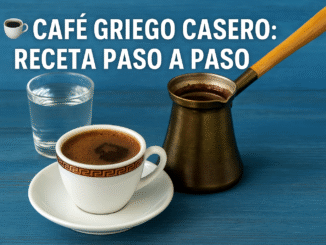 Taza de café griego casero con espuma espesa, servida junto a un briki tradicional sobre una mesa azul. Texto en la imagen: “☕ Café griego casero: receta paso a paso”