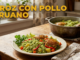 Plato de arroz con pollo peruano con arroz verde, verduras, pollo y limón, servido en mesa de cocina iluminada.
